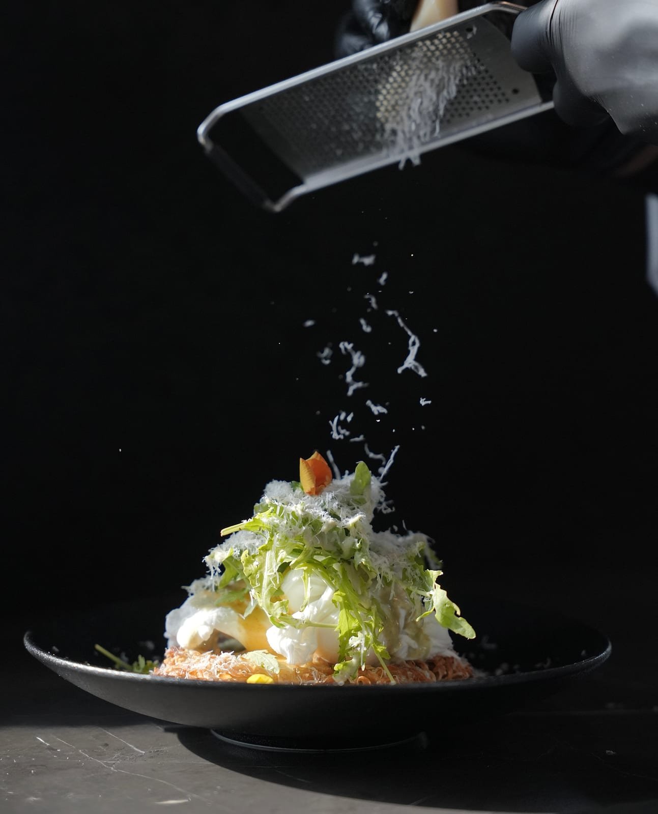 Chef grating cheese over a plated dish