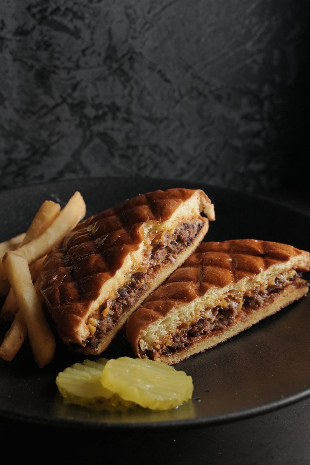 Pressed burger sandwich with fries and pickles